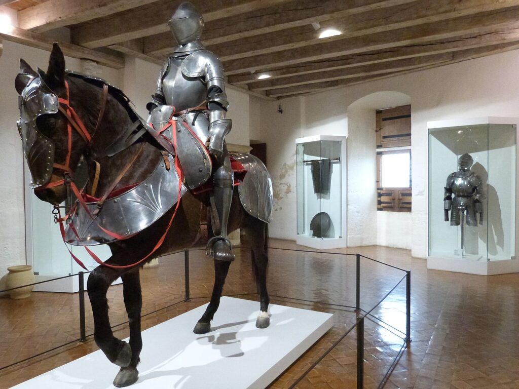 Exposé au centre de la salle des peintures, l'équipement du cavalier et de sa monture. Le cavalier est protégé par son armure de plates, le cheval, par des "bardes" (Château de Castelnaud-la-Chapelle, Dordogne) Crédit Thérèse Gaigé